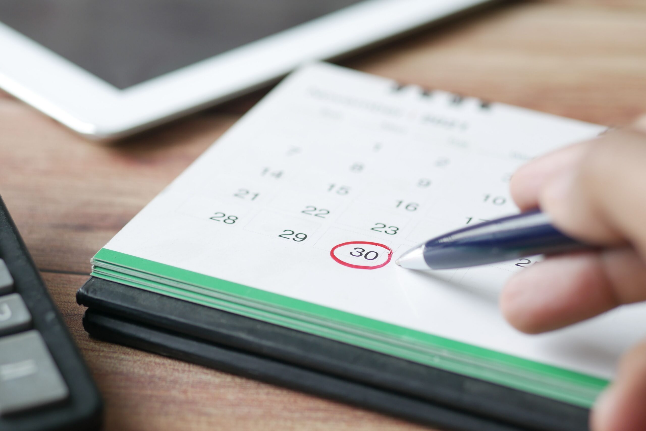 pexels-photo-11773871-11773871 Close-up shot of a hand marking a date on a calendar with a pen, emphasizing planning and scheduling.
